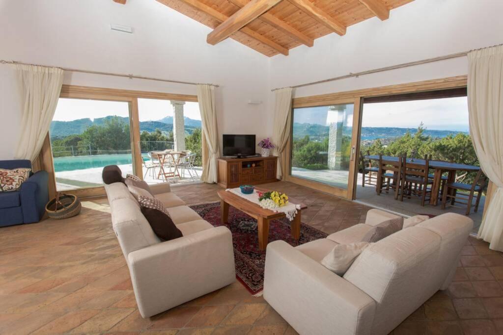 - un salon avec des canapés blancs, une table et des chaises dans l'établissement Villa Con Piscina Vista Mare, à Cala Bitta
