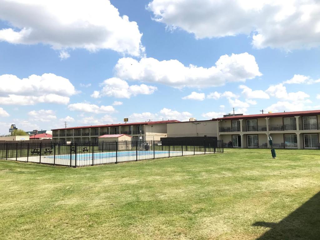 a building with a fence in front of a field at Days Inn by Wyndham Joplin in Joplin