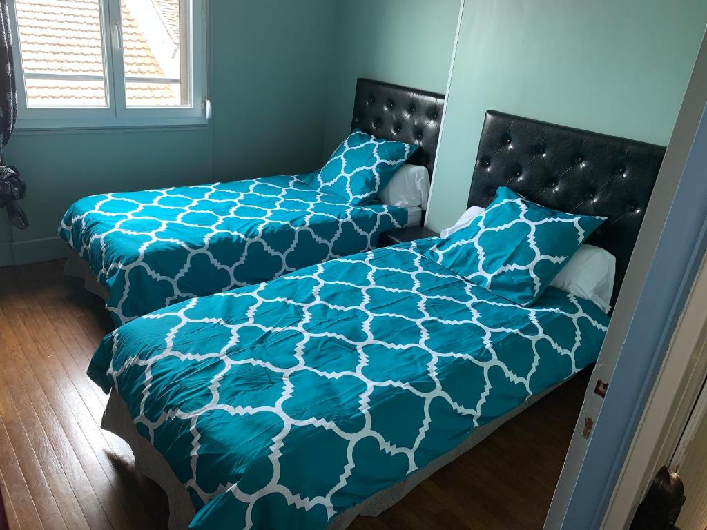 1 Schlafzimmer mit 2 Betten mit blauer Bettwäsche und einem Fenster in der Unterkunft Gîte Arcis sur Aube in Arcis-sur-Aube