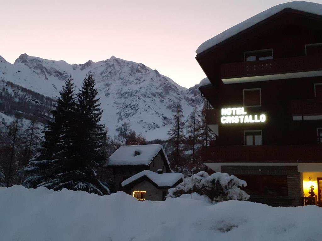 a hotel in the snow with mountains in the background at Hotel Cristallo in Macugnaga