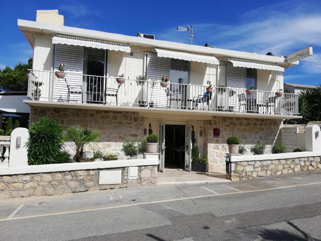 a white house with a person sitting on the balcony at Hotel Miramar- Cap d'Antibes - La Garoupe plage in Antibes