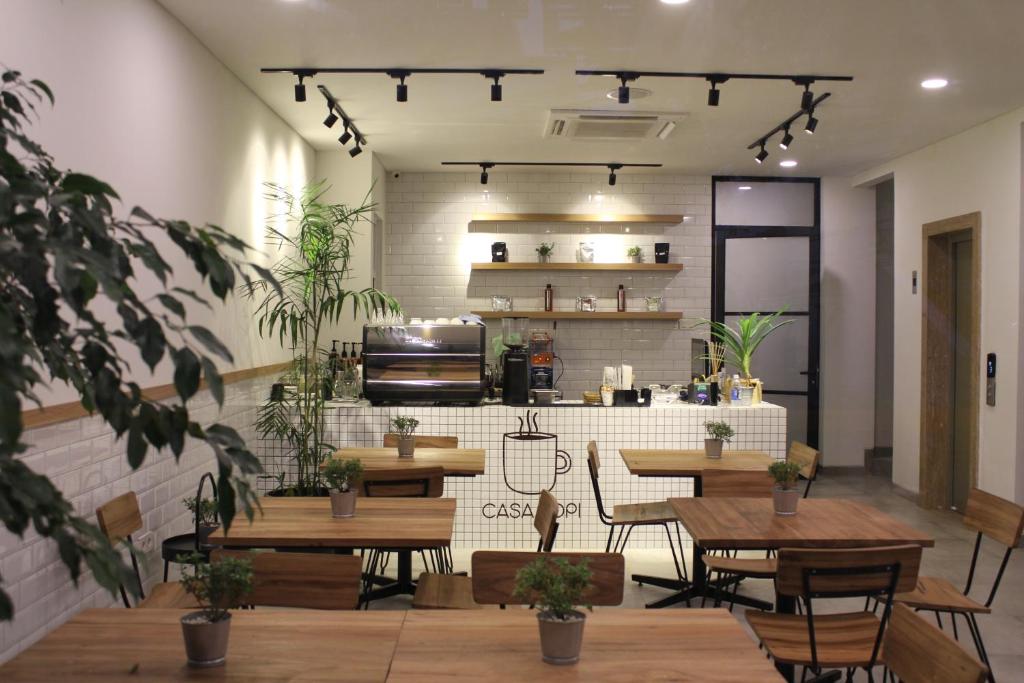 um restaurante com mesas e cadeiras e uma cozinha em Casa Living Senayan Hotel em Jakarta