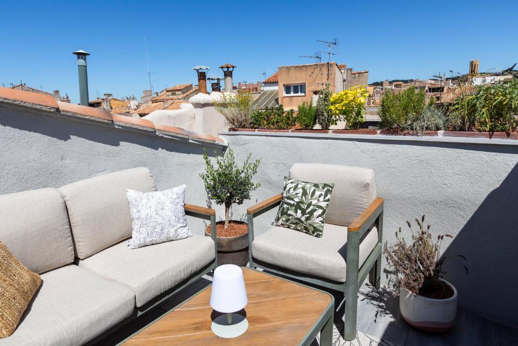 a patio with a couch and two chairs on a balcony at DUPLEX MIRABEAU - Roof terrace with panoramic view in Aix-en-Provence