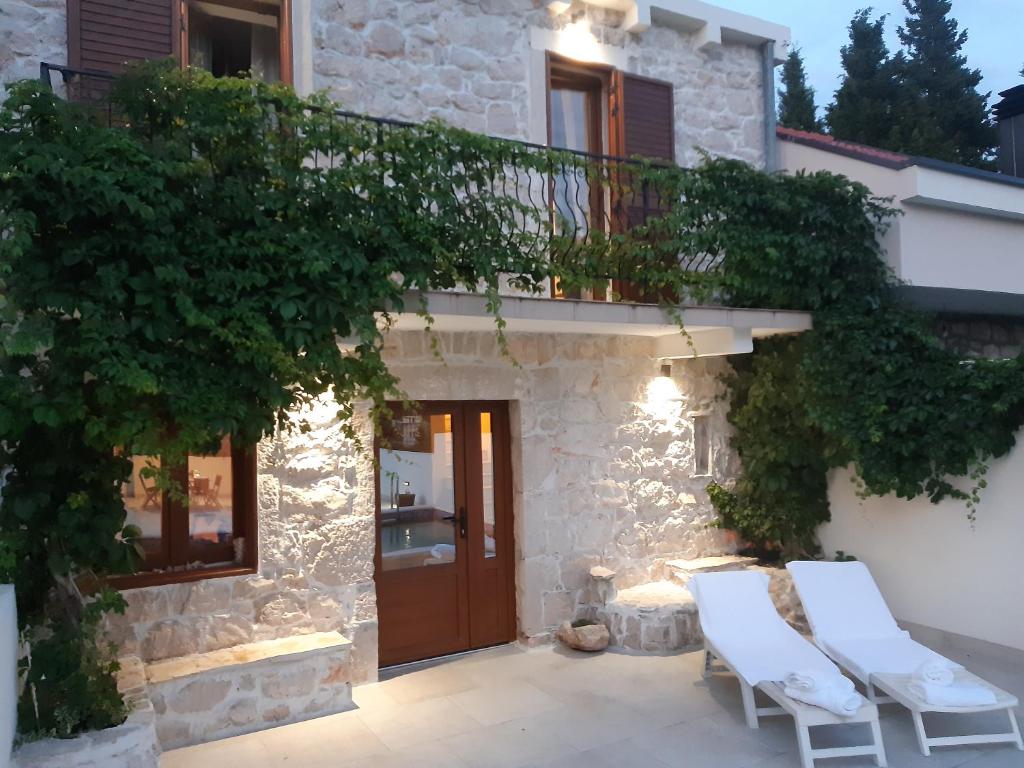 Cette maison en pierre dispose d'un balcon et de 2 chaises blanches. dans l'établissement Villa Dragi, à Klek