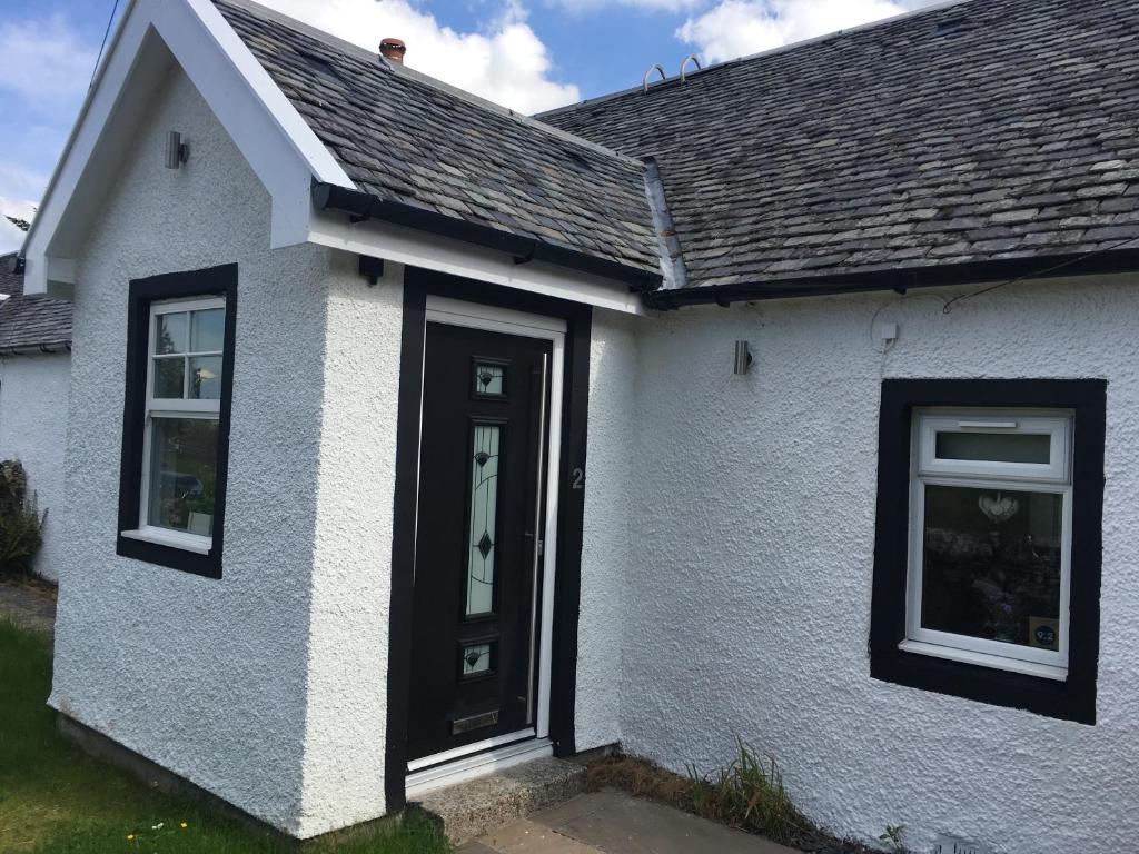 Gartocharn的住宿－Ben Lomond Cottage，白色的房子,有黑色的门和窗户