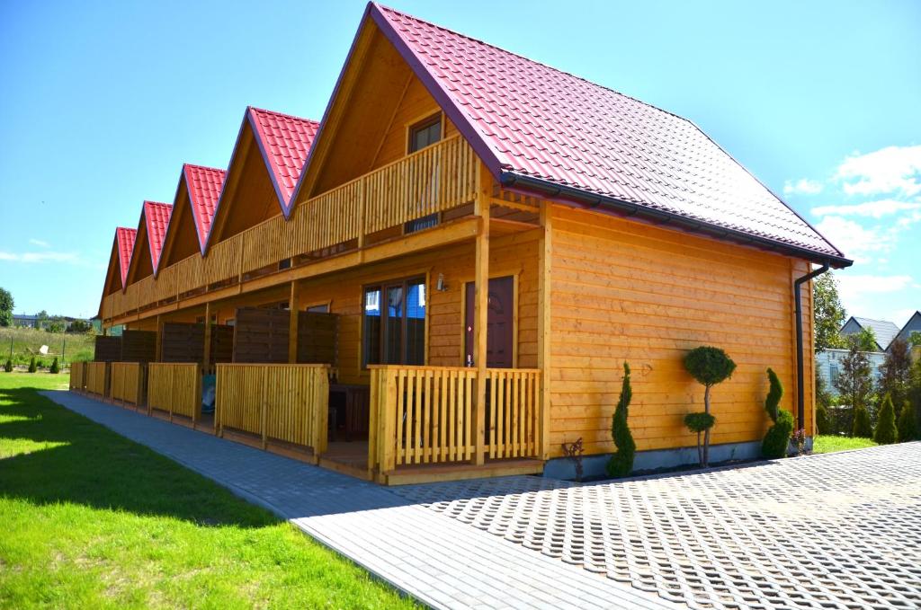 a small wooden house with a red roof at Hippalos Domki Lux in Jarosławiec