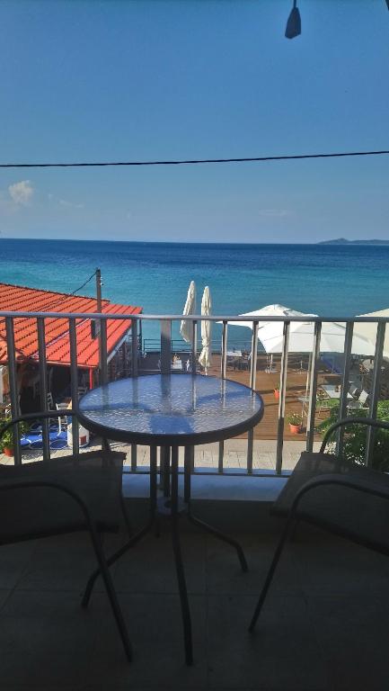 a table and chairs on a balcony with a view of the ocean at DIOLKOS APARTEMENT in Nea Roda