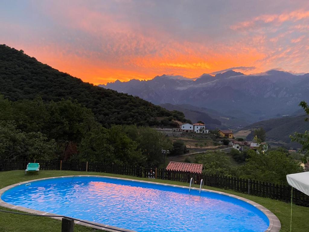 a swimming pool with a sunset in the mountains at Posada El Bosque in Mieses