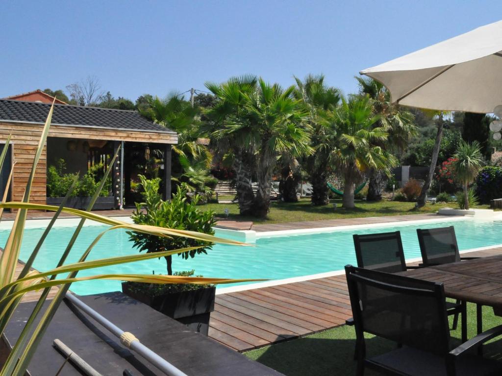 - une piscine avec une table et un parasol dans l'établissement Villa Carroubier, à La Londe-les-Maures
