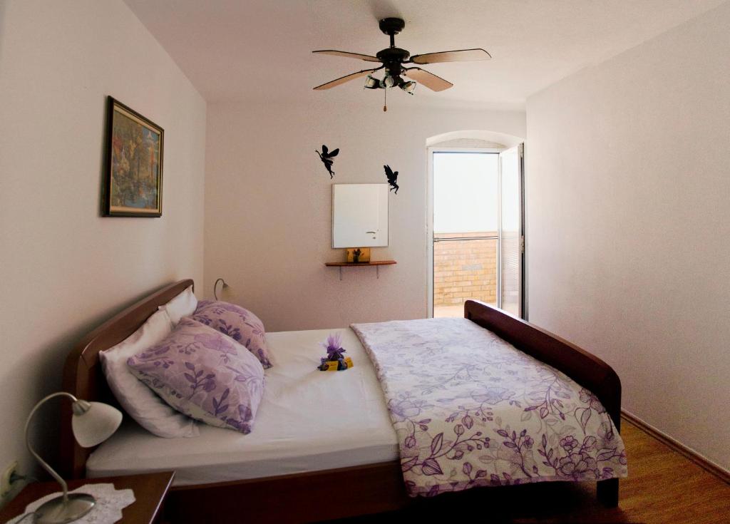 a bedroom with a bed with a ceiling fan and a window at Apartment Percic in Tar
