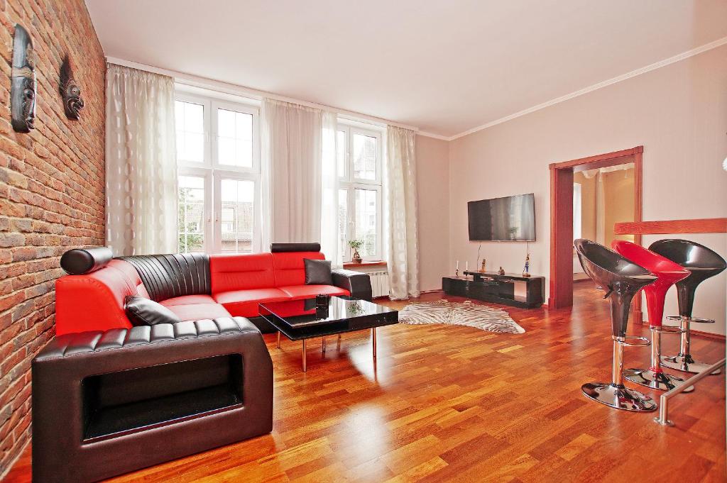 グダニスクにあるBaySide Apartments MainCityのリビングルーム(赤いソファ、椅子付)