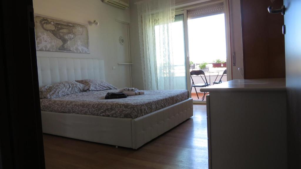 1 dormitorio con 1 cama y puerta a un balcón en Luna Rossa Rooms, en Cagliari