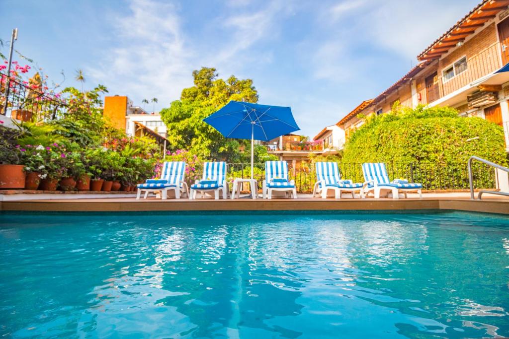 een groep stoelen en parasols naast een zwembad bij Hotel Posada De Roger in Puerto Vallarta