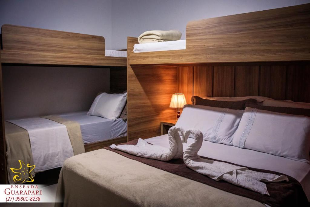 Cette chambre d'hôtel comprend deux lits et un lit avec des chaussettes. dans l'établissement CONFORTO IMBATIVEL - 25 metros do MAR - 2 Quartos com AR CONDICIONADOS SPLIT, Air Fryer, WI-FI, Netflix, Disney Plus, Star Plus, HBO Max, Guarda Sol, Cadeiras de Praia - 8 pessoas com muito conforto!, à Guarapari