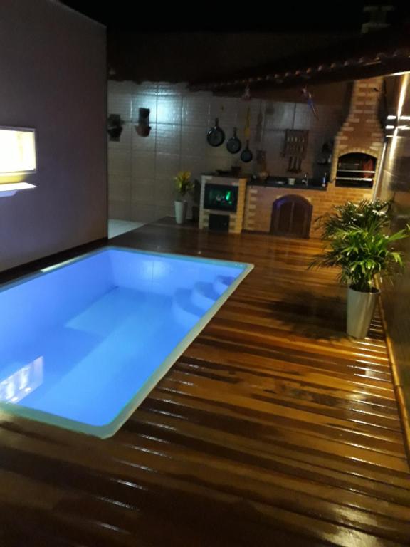 um quarto com uma grande piscina azul num piso de madeira em casa sao pedro da aldeia em São Pedro da Aldeia