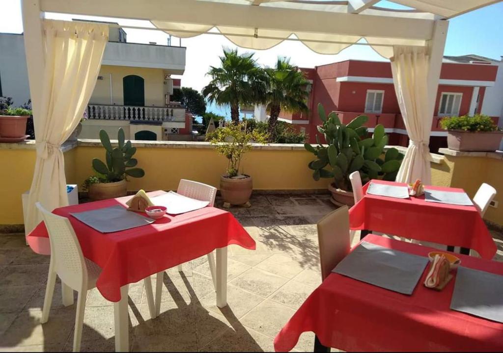 - deux tables et des chaises sur une terrasse avec un tissu de table rouge dans l'établissement B&B Barone, à Castro di Lecce