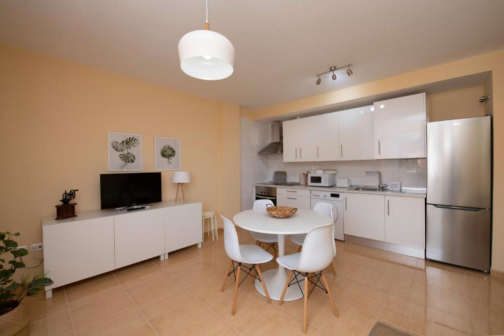 a kitchen with white cabinets and a table and chairs at Miramar 1 in San Sebastián de la Gomera