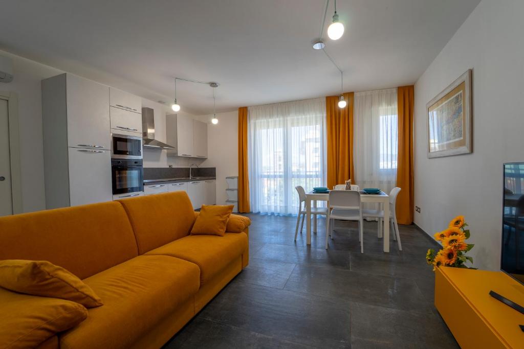 a living room with a yellow couch and a kitchen at La Luna nel Golfo - Appartamenti a Follonica in Follonica
