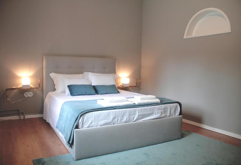 um quarto com uma cama grande e 2 almofadas azuis em Genius Loci Guesthouse em Matosinhos