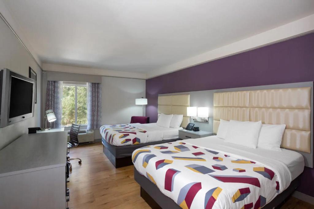 a hotel room with two beds and a flat screen tv at La Quinta by Wyndham Mobile - Daphne in Daphne