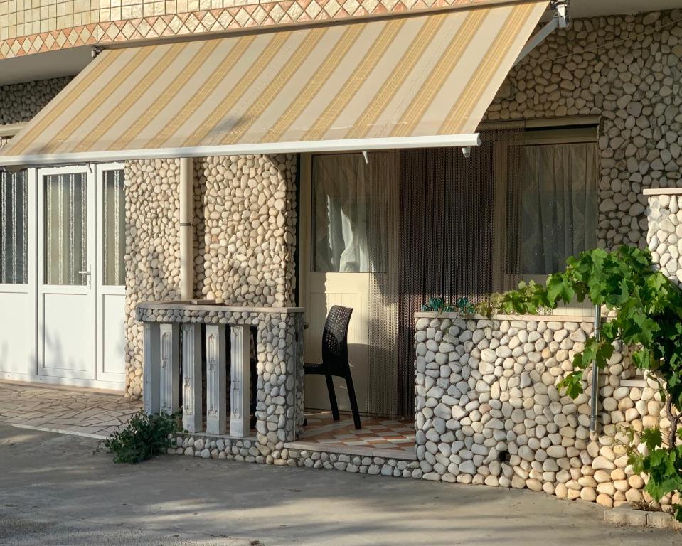 Un porche delantero con una pared de piedra y una silla. en casa sole, en Peschici