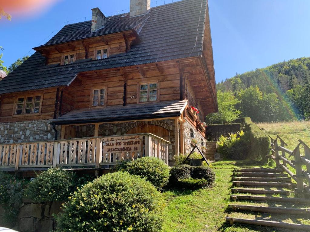 uma antiga casa de madeira com um alpendre de madeira e escadas em Wynajem Pokoi-Willa Pod Smrekami em Zakopane