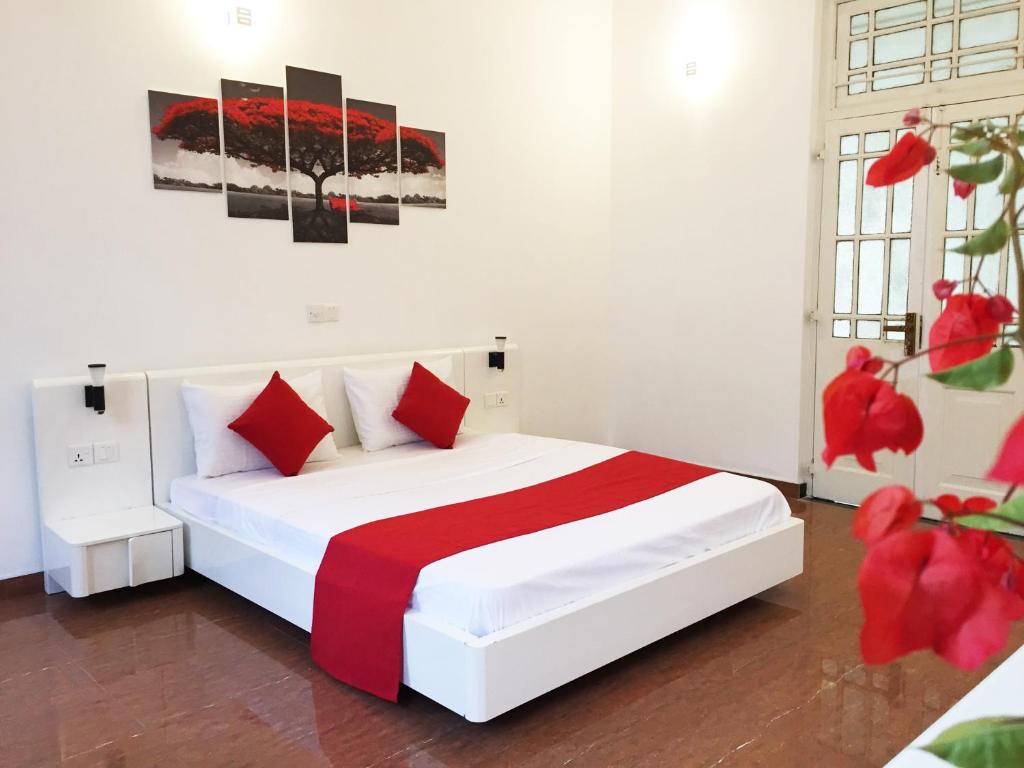 um quarto com uma cama branca e almofadas vermelhas em Grand Villa Negombo em Negombo