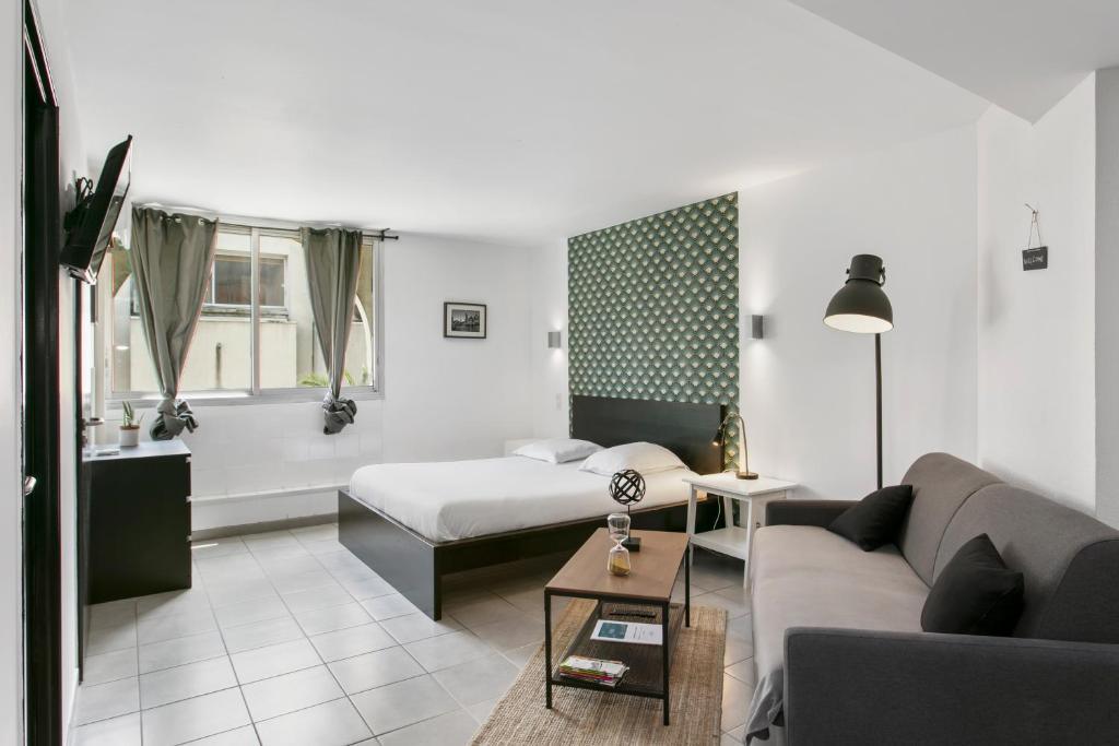 een hotelkamer met een bed en een bank bij Coeur Urbain Apartments - Place de la Comédie in Montpellier