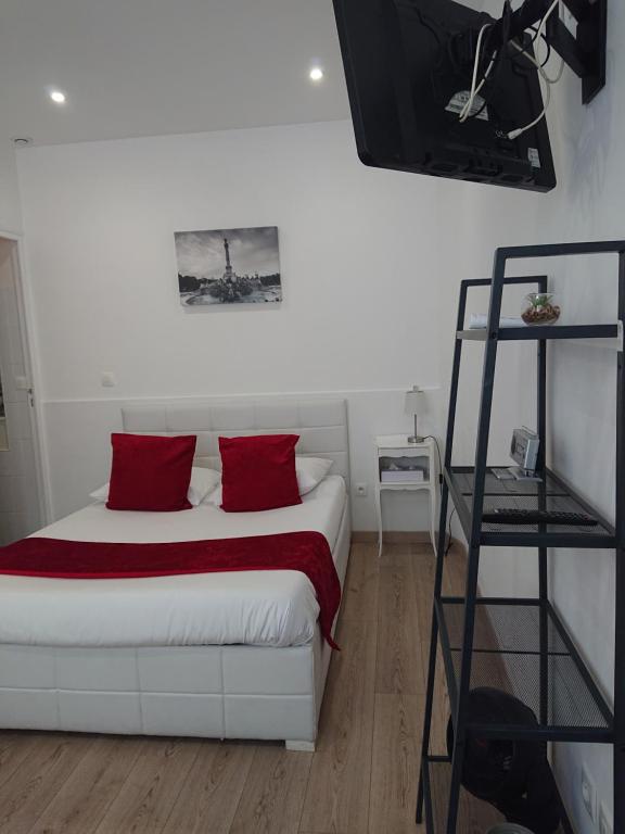 - une chambre avec un lit blanc et des oreillers rouges dans l'établissement Petit studio à BORDEAUX CHARTRONS / JARDIN PUBLIC (6), à Bordeaux