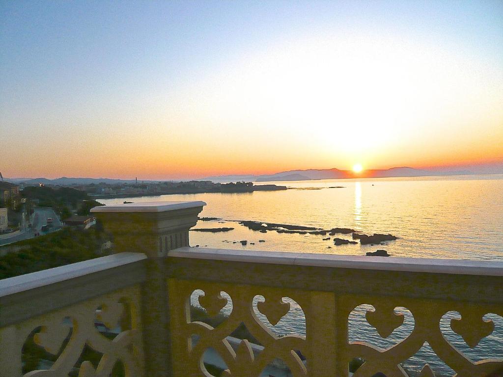 uma vista para o oceano a partir de uma varanda ao pôr-do-sol em Villa Andromeda em Chania Town