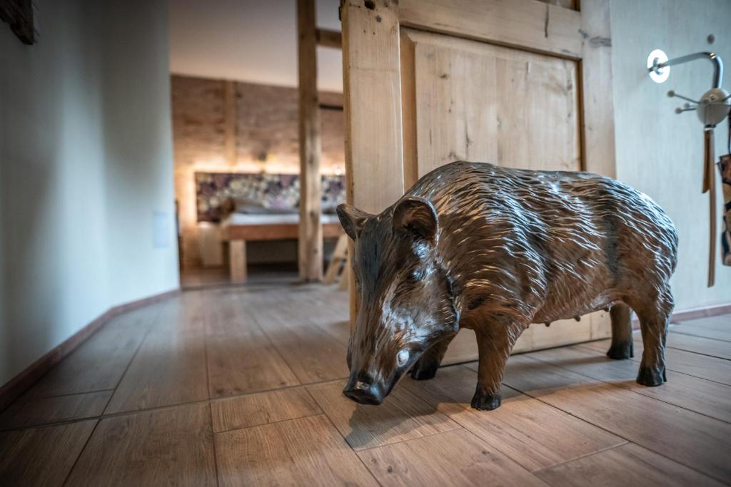 una estatua de un cerdo marrón en un suelo de madera en Ates Hütte, en Ilsenburg