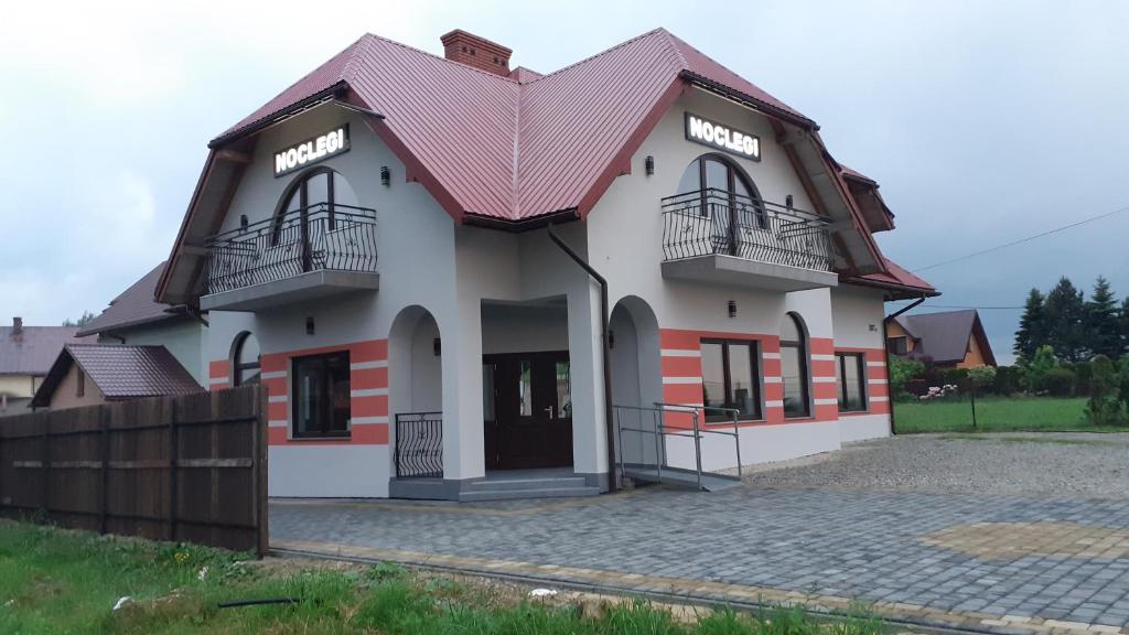 a large white building with a red roof at Noclegi Damianek in Nowy Targ