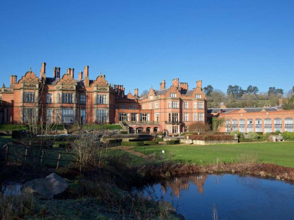 uma casa grande com um lago em frente em The Welcombe Golf & Spa Hotel em Stratford-upon-Avon