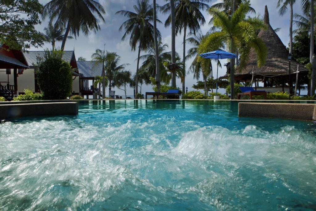 einen Pool mit blauem Wasser und Palmen in der Unterkunft Dewshore Resort in Baan Tai