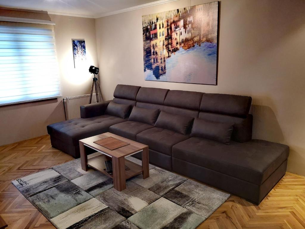 a living room with a brown couch and a table at Apartman VILLA Cacak in Čačak