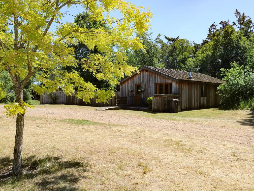 a barn with a tree in front of a yard at Meadow View in East Harling