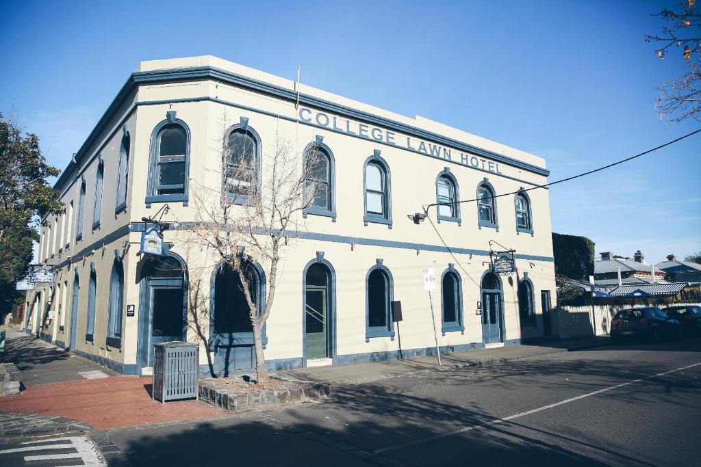 um velho edifício branco na esquina de uma rua em College Lawn Hotel em Melbourne