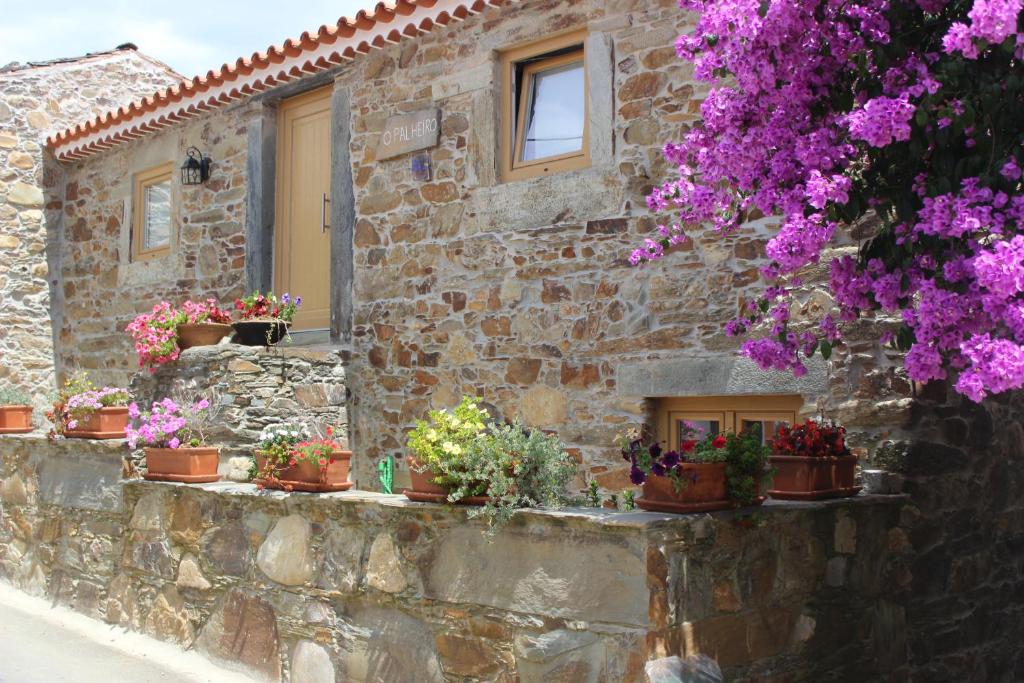 un bâtiment en pierre avec des plantes en pot sur un mur dans l'établissement O Palheiro - Vista Panorâmica e Jacuzzi, à Sobreira Formosa