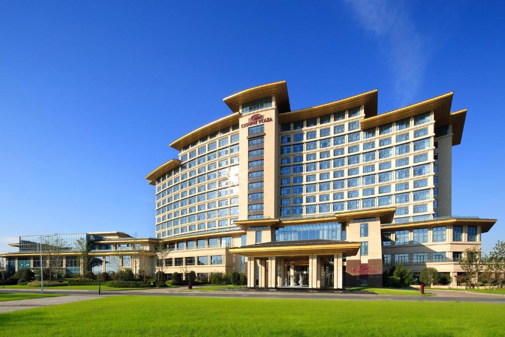 揚州市にあるクラウン プラザ 揚州の芝生の前に建つ大きなホテルです。