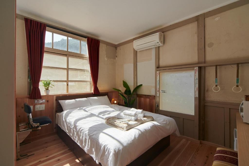 um quarto com uma cama com lençóis brancos e uma janela em NIPPONIA HOTEL KOYAsan pilgrimage railway - Vacation STAY 83808 em Kudoyama