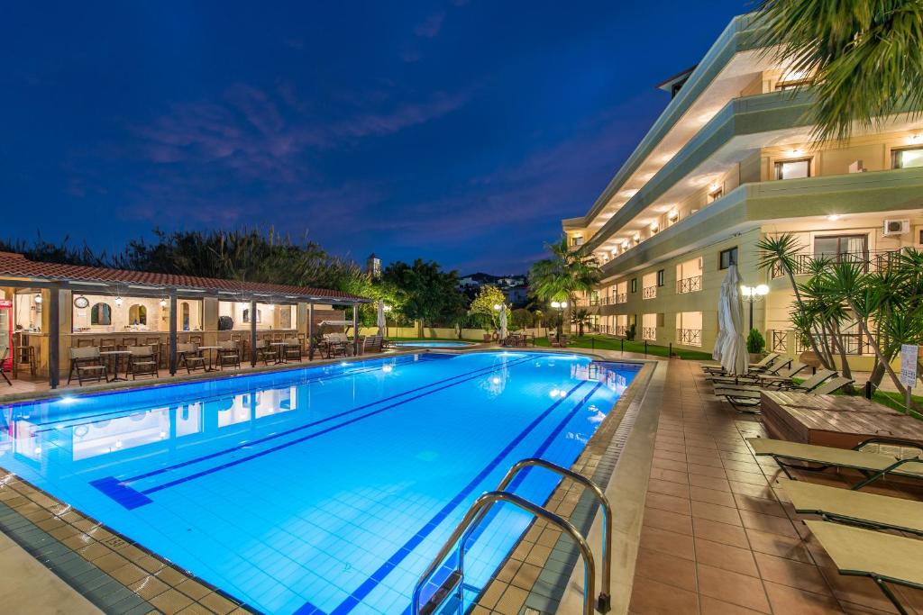 a swimming pool in front of a hotel at night at Mirtilos Studios & Apartments in Kissamos