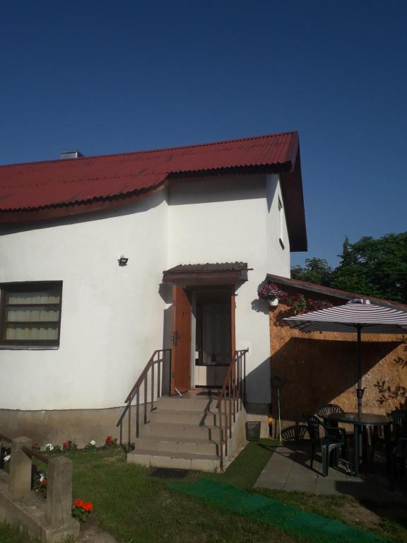 a white house with stairs and a table and an umbrella at Ginto nakvynės namai in Vilnius