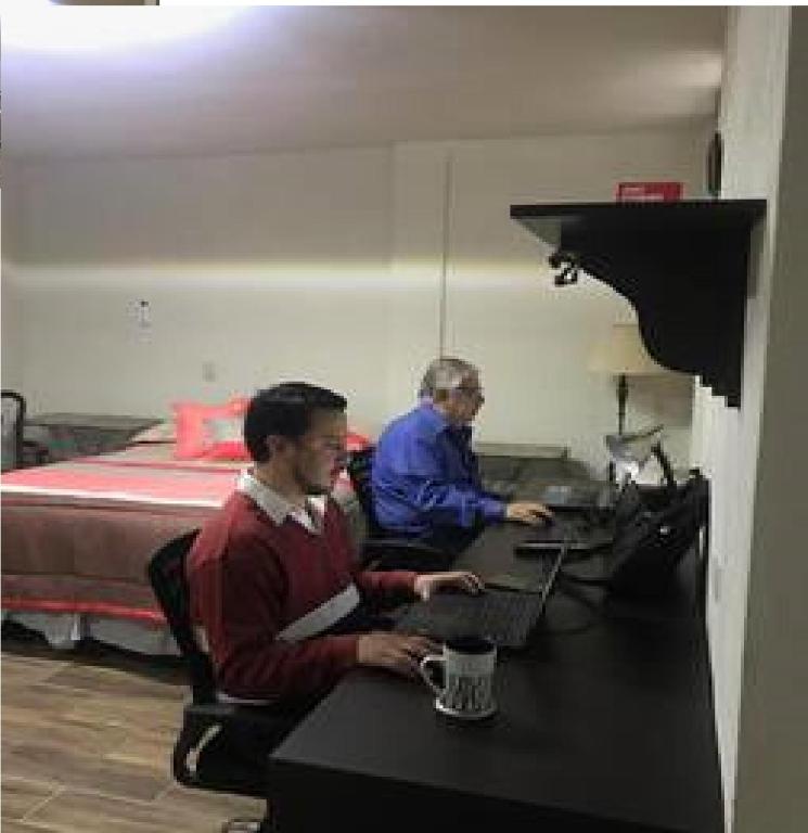 two men sitting at a desk in a room with a bed at Tec, Brisas y Sur de Mty 54633 in Monterrey