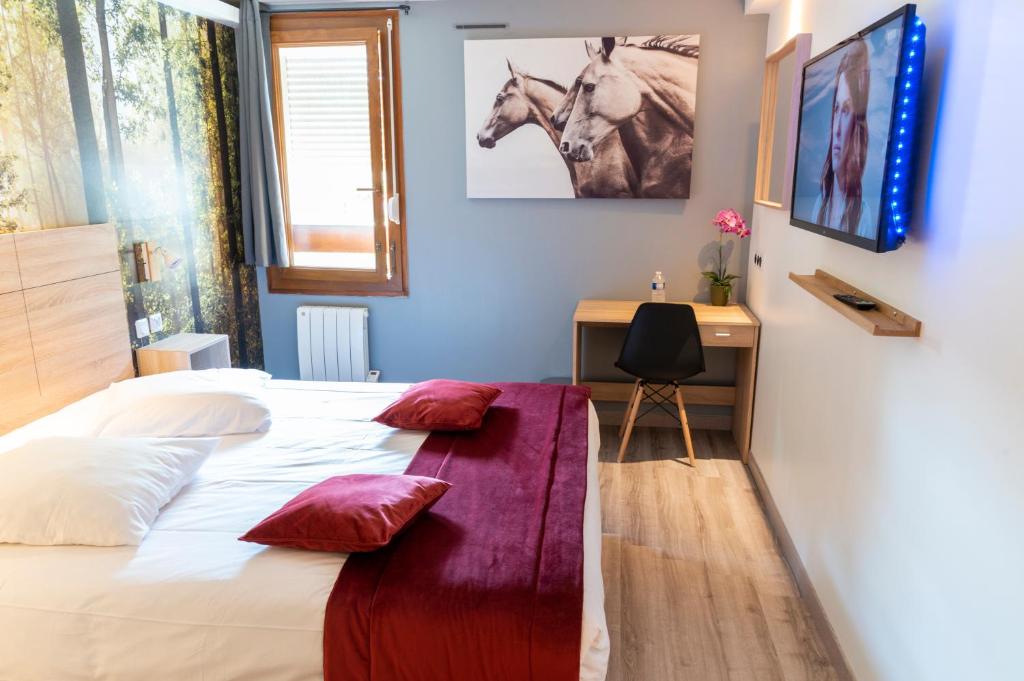 una camera da letto con letto con cuscini rossi e scrivania di Hôtel Bagatelle Paris Nord Roissy CDG a Goussainville