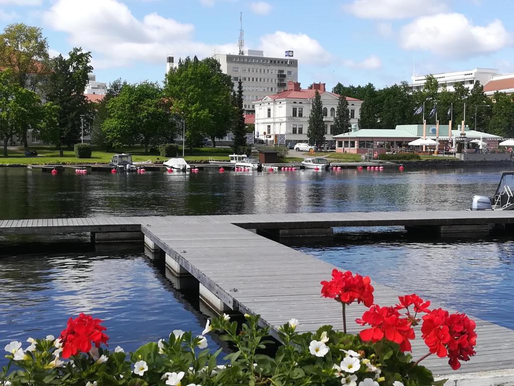 a dock with red flowers on a river with buildings at Savonlinna Rentals in Savonlinna