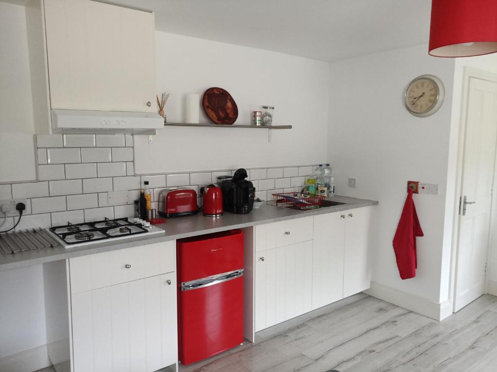 una cucina con frigorifero rosso e armadietti bianchi di Pier Road Cottage, Croagh Patrick a Westport