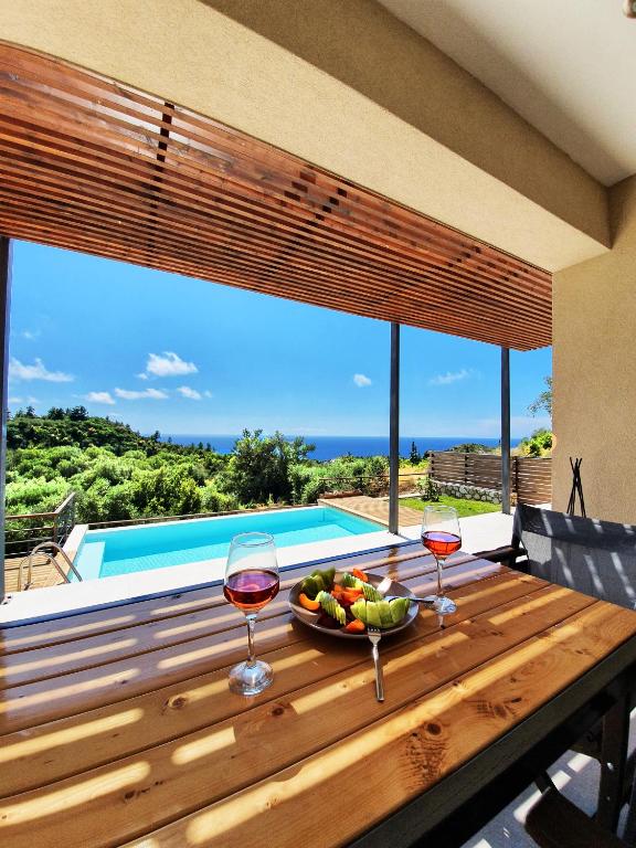 a table with two glasses of wine and a bowl of fruit at euphoria villas - Gaia & Aura in Agios Nikitas
