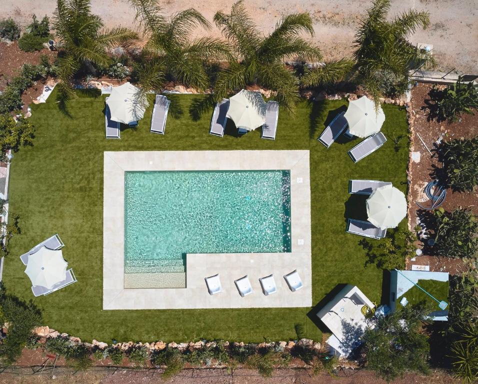 an overhead view of a swimming pool and lawn with umbrellas at Residence I Faraglioni in Scopello