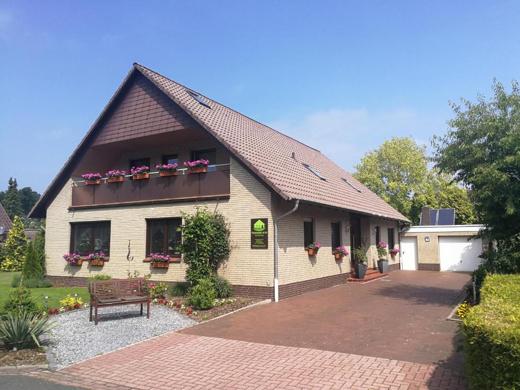 ein Gebäude mit Blumenkästen an den Fenstern und einer Bank in der Unterkunft Ferienwohnung Am See in Rhauderfehn