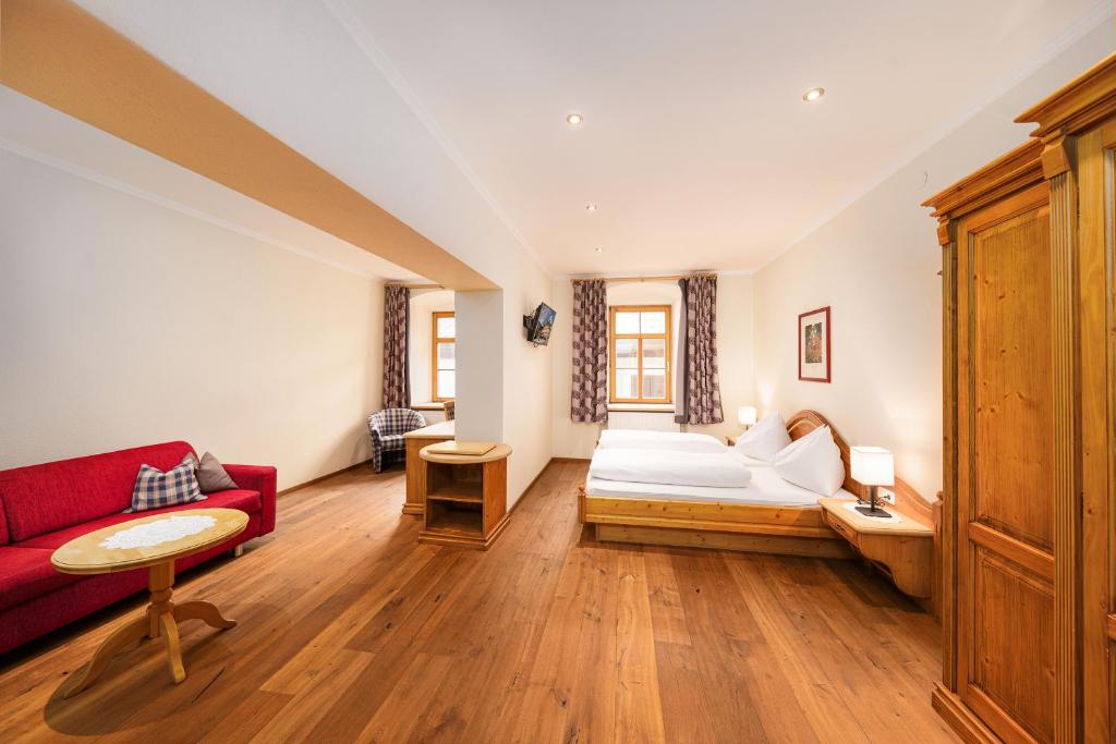 ein Wohnzimmer mit einem roten Sofa und einem Bett in der Unterkunft Hotel Heitzmann in Mittersill